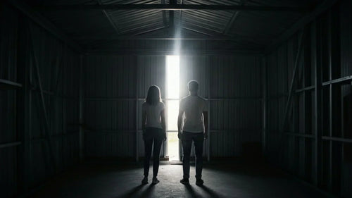 Man and woman standing inside a steel structure room looking out