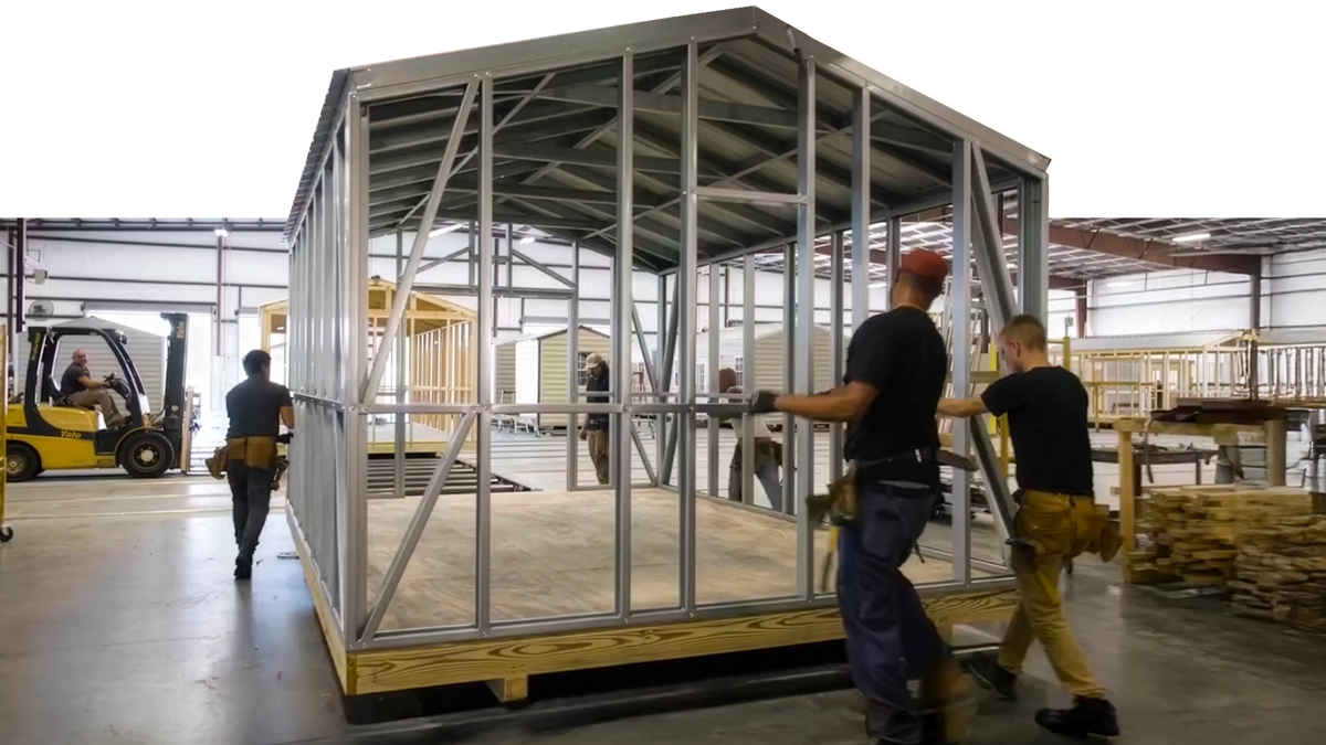Workers assembling a metal frame structure in a warehouse.